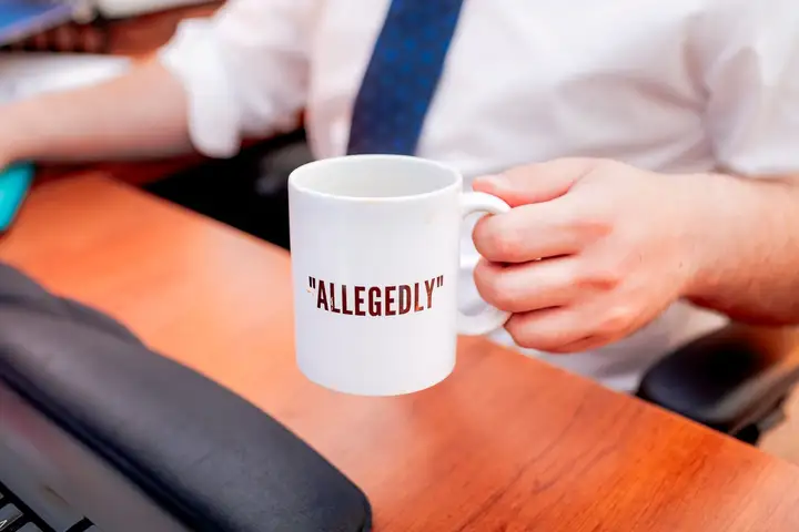 Une tasse portant l'inscription 'allegedly' sur un bureau du cabinet à Moncton