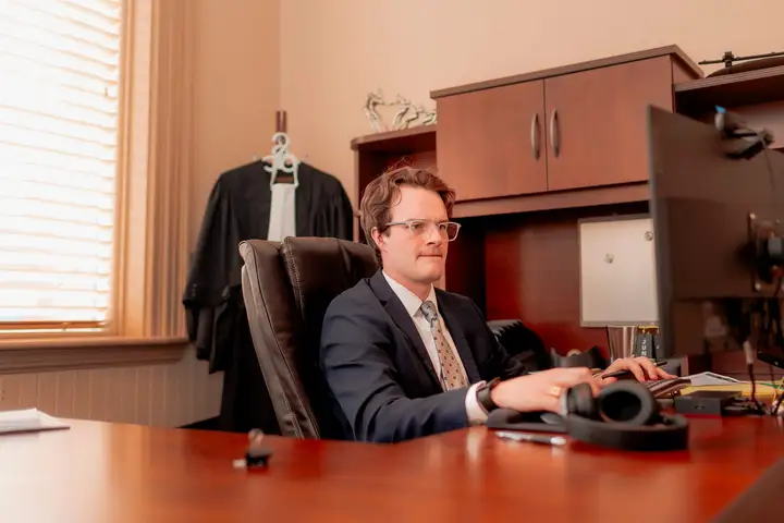 Un bureau dans les locaux du cabinet à Moncton, avec des toges d'avocat suspendues derrière